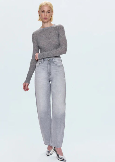 Woman wearing a gray sweater and light gray jeans on a white background