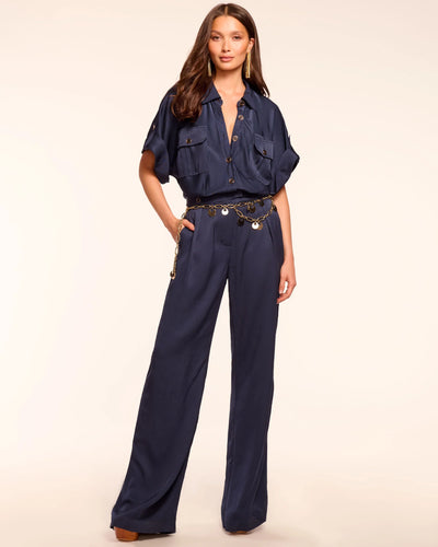 Woman wearing a navy blue jumpsuit with a belt on a beige background